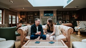 A spacious living room with leather sofas, a high ceiling with skylight, and a fireplace. - The Spa Hotel at Ribby Hall Village (Preston)