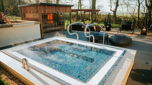 A hot tub with a wooden deck and a pergola in the background. - The Spa Hotel at Ribby Hall Village (Preston)