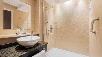 A modern bathroom with a granite countertop, a white sink, a glass-enclosed shower, and a bathtub.