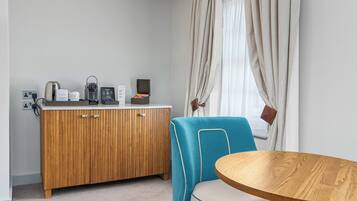 A room with a wooden cabinet, a blue chair, and a round wooden table.