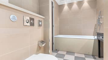 Un baño moderno con inodoro, secamanos y zona de ducha.