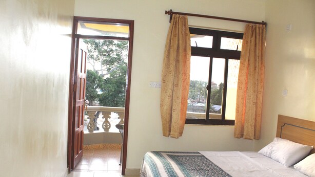 Une chambre à coucher avec un lit, des rideaux, une fenêtre et un balcon.