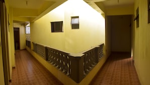 Un couloir étroit avec un garde-corps incurvé, un sol carrelé et une porte au fond.