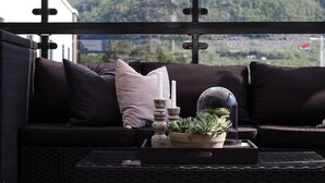 A dark-colored sofa with cushions, a potted plant, and a candle on a tray.