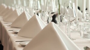 A long table set with white napkins, clear glassware, and white candles.