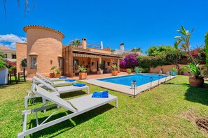 Een buitenzwembad, ligstoelen bij het zwembad