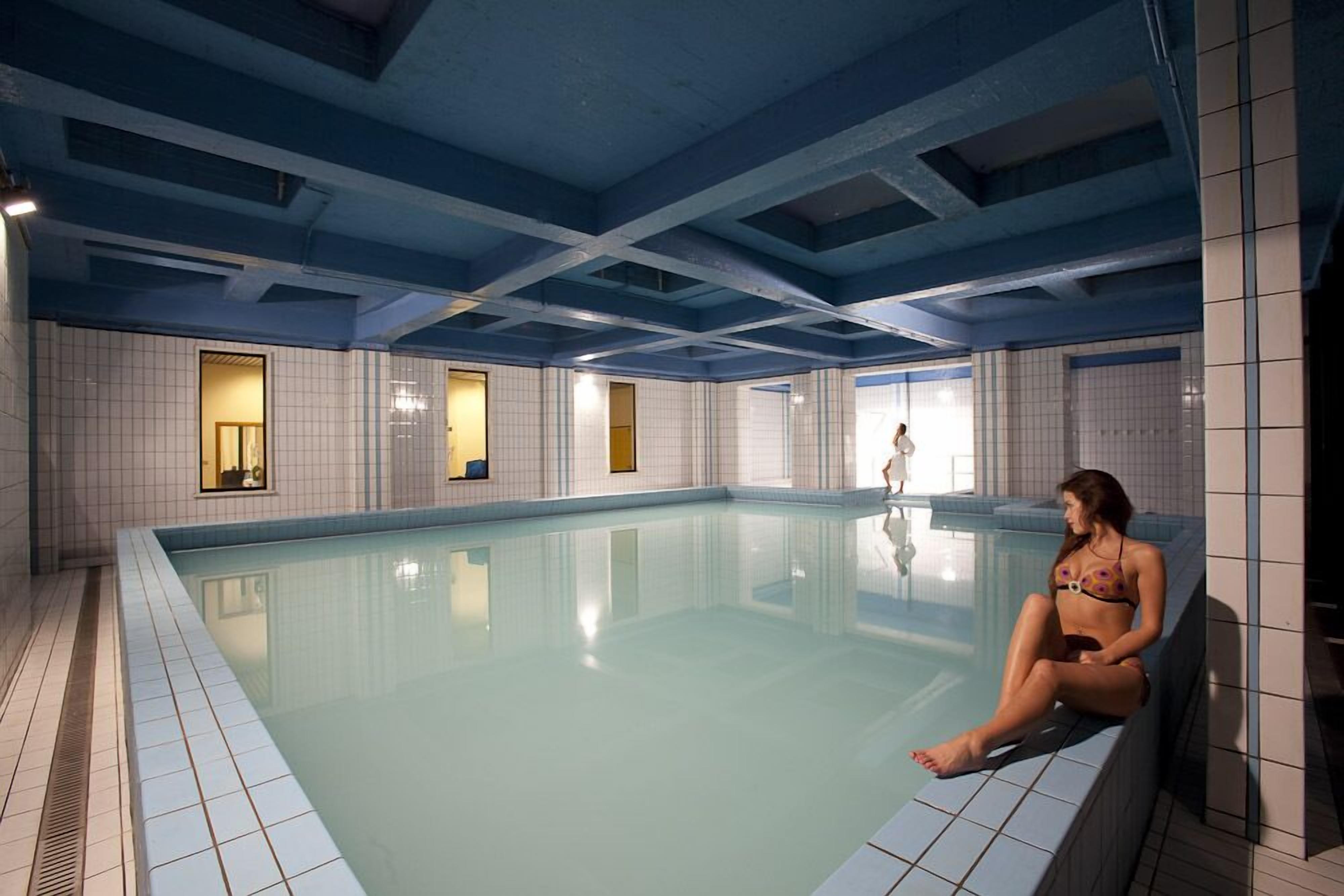 Una piscina interior con paredes de azulejos y techo azul.