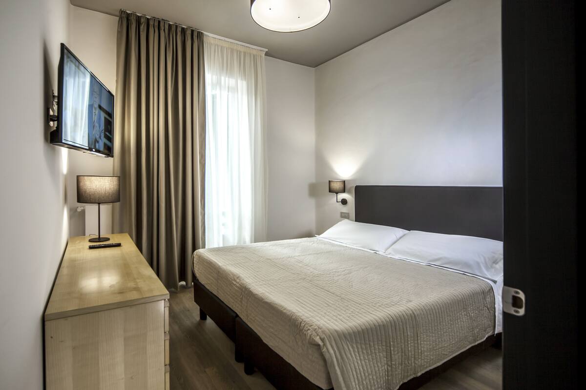 Une chambre d’hôtel avec un lit, un bureau, une lampe et un téléviseur.