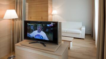 A modern living room with a flat-screen TV on a wooden stand, a white sofa, and a lamp.