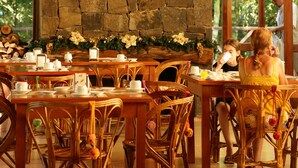 A restaurant with stone walls, wooden furniture, and hanging paper lanterns.