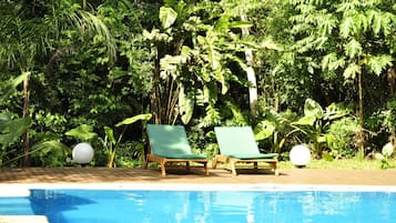 Una piscina al aire libre, sillones reclinables de piscina