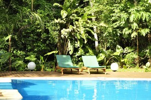 A poolside area with two green lounge chairs and a wooden deck. - Tierra Guarani Lodge de Selva (Puerto Iguazú)