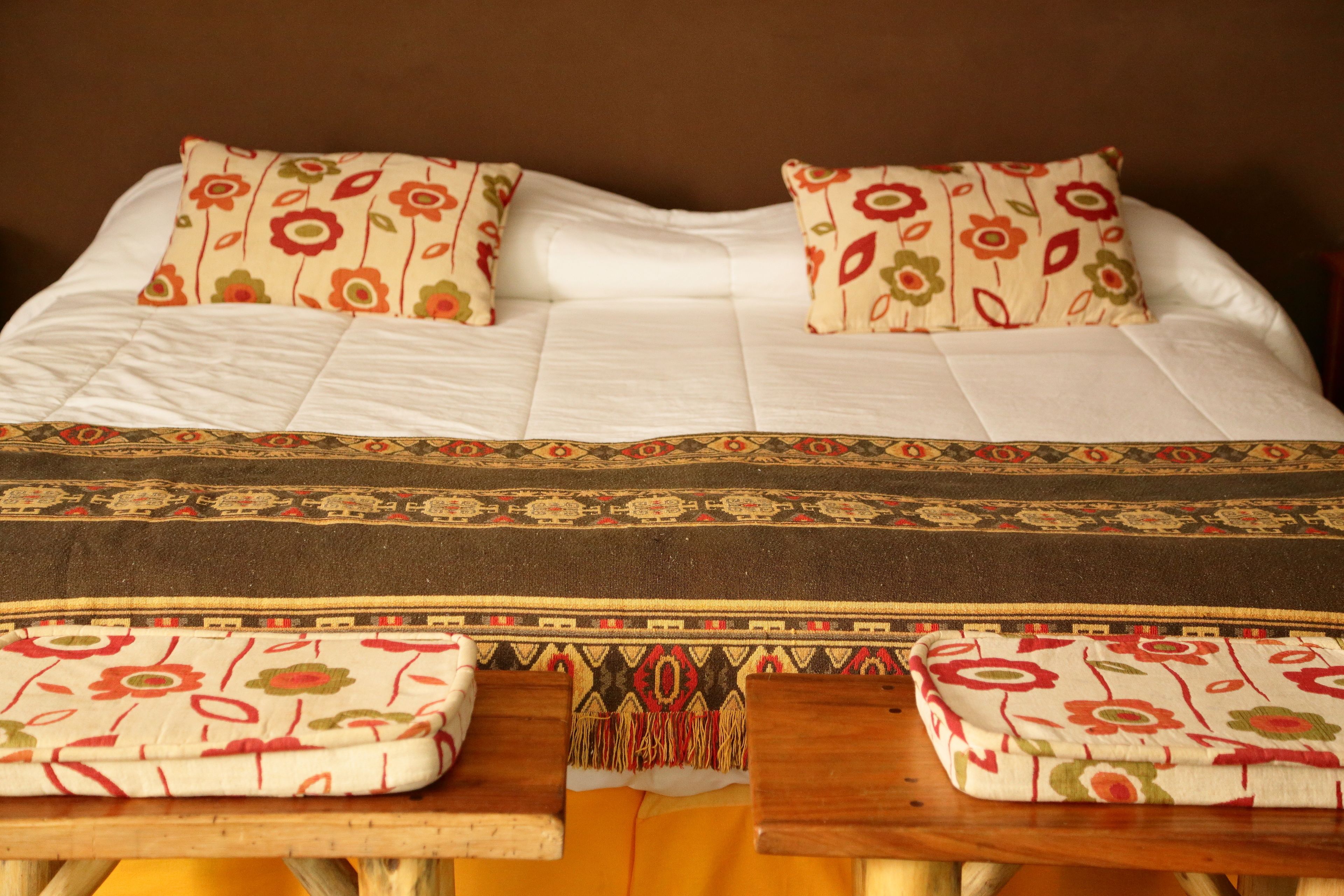 A neatly made bed with floral-patterned pillows and a decorative bedspread.