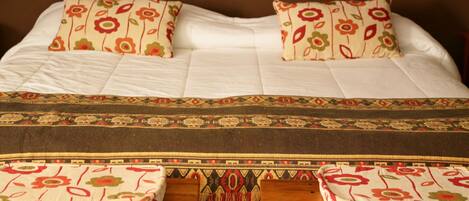 A neatly made bed with floral-patterned pillows and a decorative bedspread.