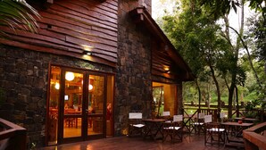 A stone building with wooden exterior and a deck with tables and chairs.