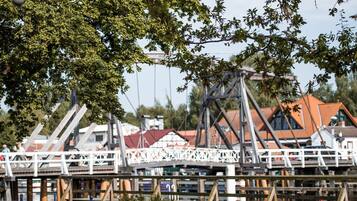 Eine hölzerne Brücke mit weißer Brüstung, die zu einem Gebäude mit rotem Dach führt.