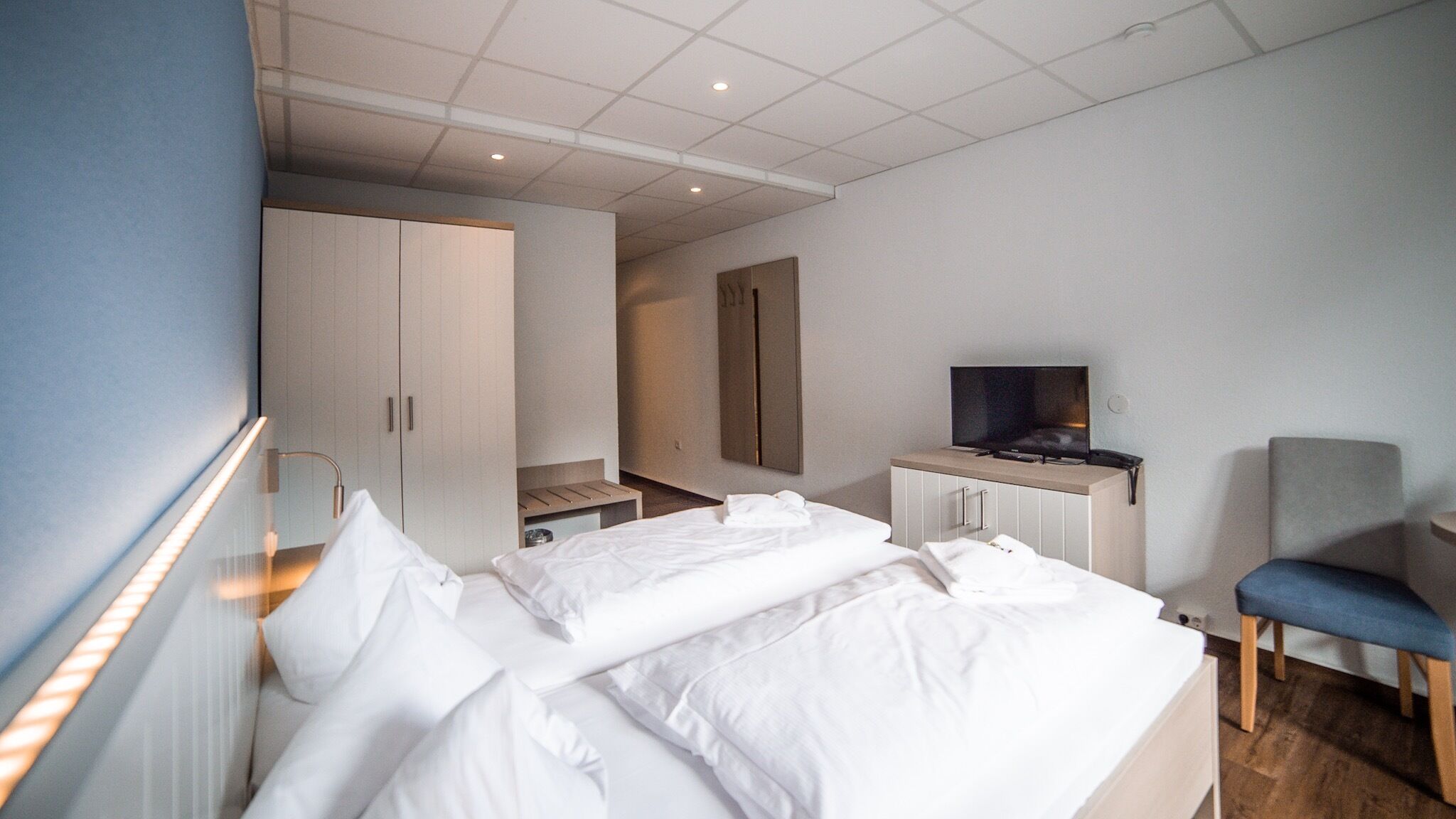Une chambre d’hôtel avec deux lits, une télévision, un bureau et une chaise.