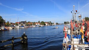 A marina with boats docked, a clear sky, and buildings in the background. - Hotel zur Fähre (Greifswald)