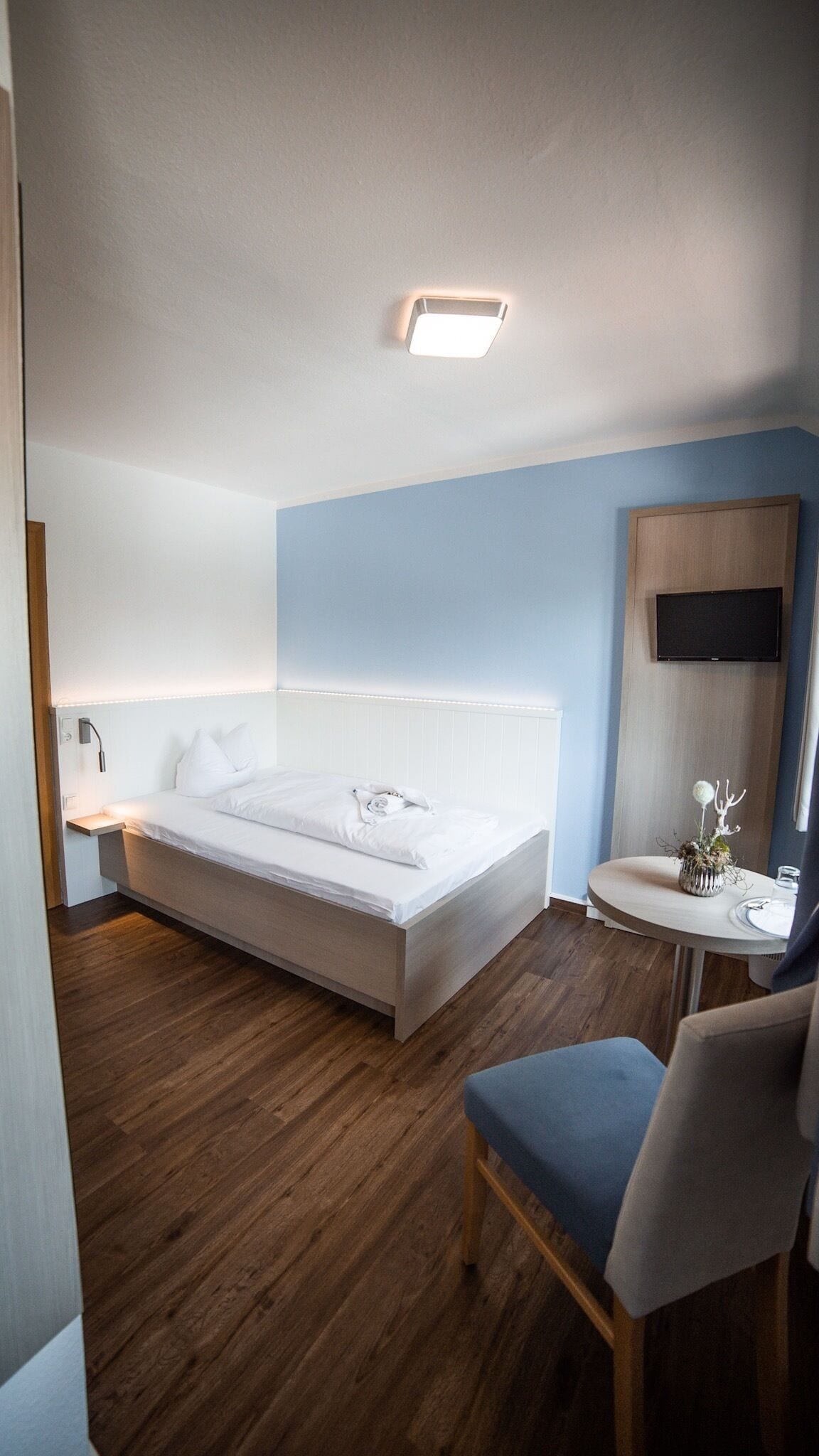 Una habitación de hotel moderna con una cama grande, una mesita de noche y un escritorio pequeño con una silla.