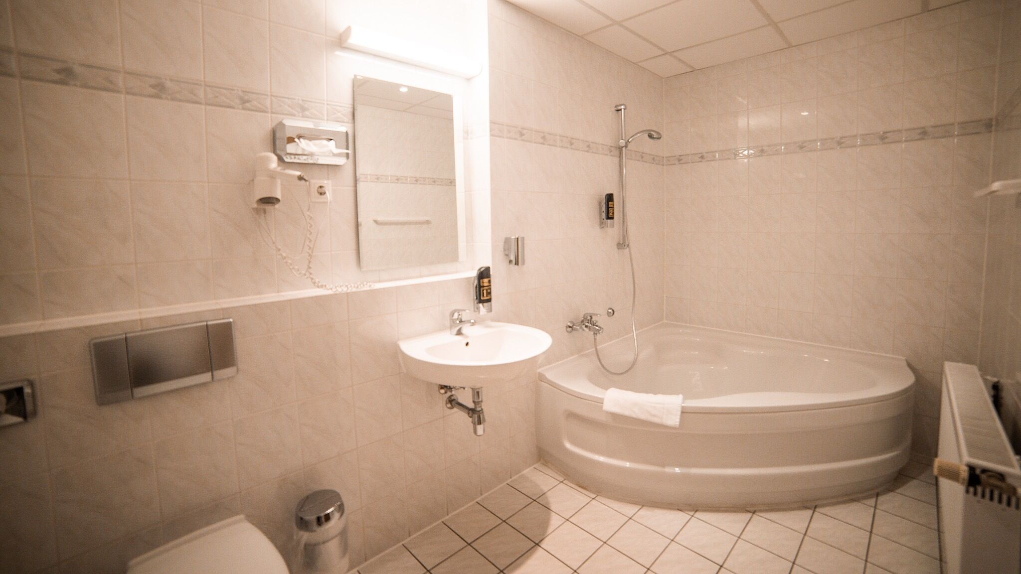 A bathroom with a sink, mirror, toilet, and a freestanding bathtub.