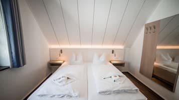Habitación de hotel con dos camas, un espejo grande y un armario de madera.
