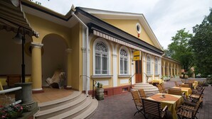 A building with a yellow facade, arched windows, and a sign indicating a restaurant.