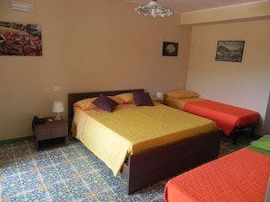 Habitación de hotel con dos camas, una mesita de noche, una lámpara y piso con diseño.