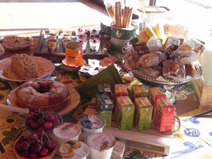 Variedad de alimentos como pasteles, frutas y productos envasados sobre una mesa.