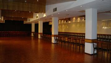 A spacious hall with rows of chairs and a wooden floor.