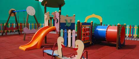 Un parque infantil con un sube y baja, un tobogán y diversas estructuras de juego.