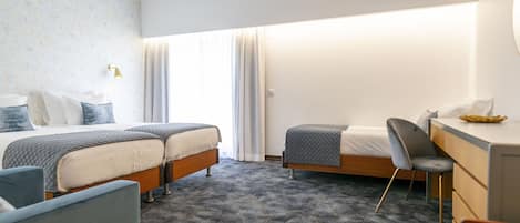 A hotel room with two beds, a desk, and a chair.