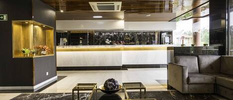 A modern lobby with a reception desk, seating area, and a decorative bowl on a glass table.