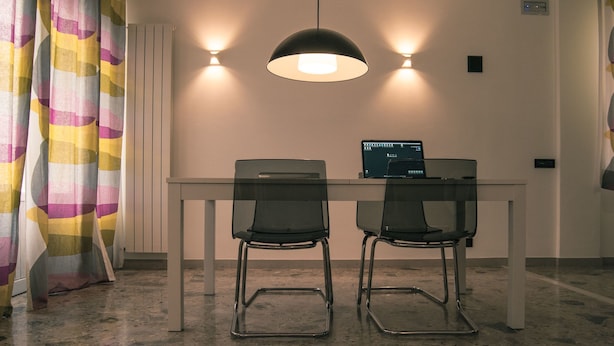 A modern dining area with a white table, two black chairs, and a pendant light. - B&B La Casa Di Adua (Porto Sant'Elpidio)