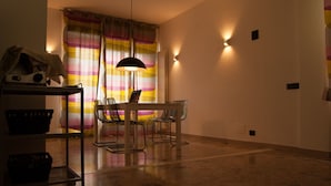 A dining area with a table and chairs, a hanging light fixture, and a striped curtain. - B&B La Casa Di Adua (Porto Sant'Elpidio)