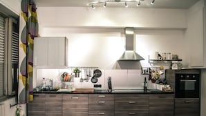 A modern kitchen with dark wood cabinets, a stainless steel range hood, and a black oven. - B&B La Casa Di Adua (Porto Sant'Elpidio)