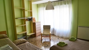 A hotel room with two beds, a chair, a desk with a chair, and a radiator. - B&B La Casa Di Adua (Porto Sant'Elpidio)
