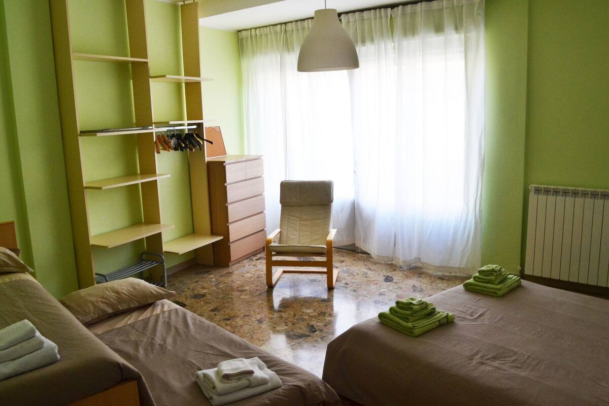 Een hotelkamer met twee bedden, een stoel, een bureau met stoel en een radiator.