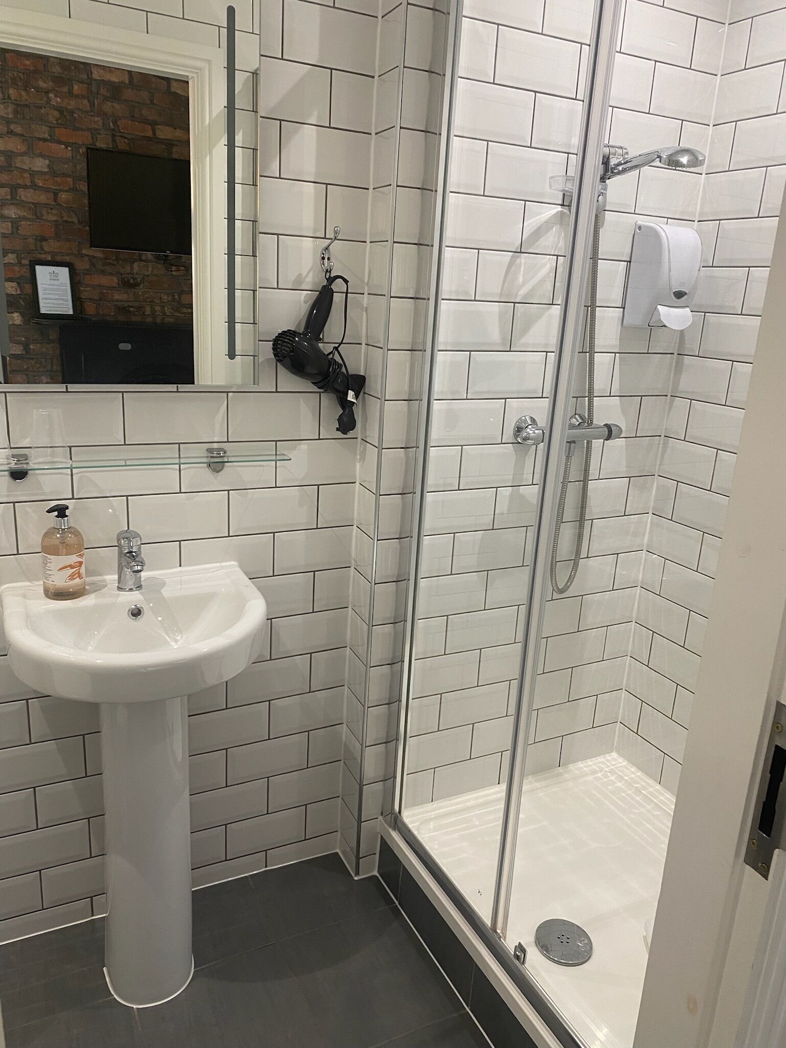 Un baño con un lavabo blanco, cabina de ducha de vidrio y un espejo sobre el lavabo.