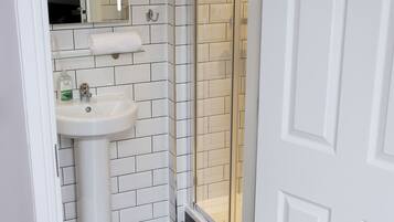 A bathroom with a white sink, mirror, and shower enclosure.