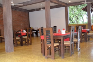 Un restaurante con mesas y sillas de madera, paredes de ladrillo y piso de baldosas.
