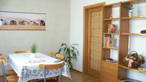 A dining area with a table set for four, surrounded by chairs, a bookshelf with books and decorative items, and a potted plant. - Capri residence in Vicenza (vicenza)