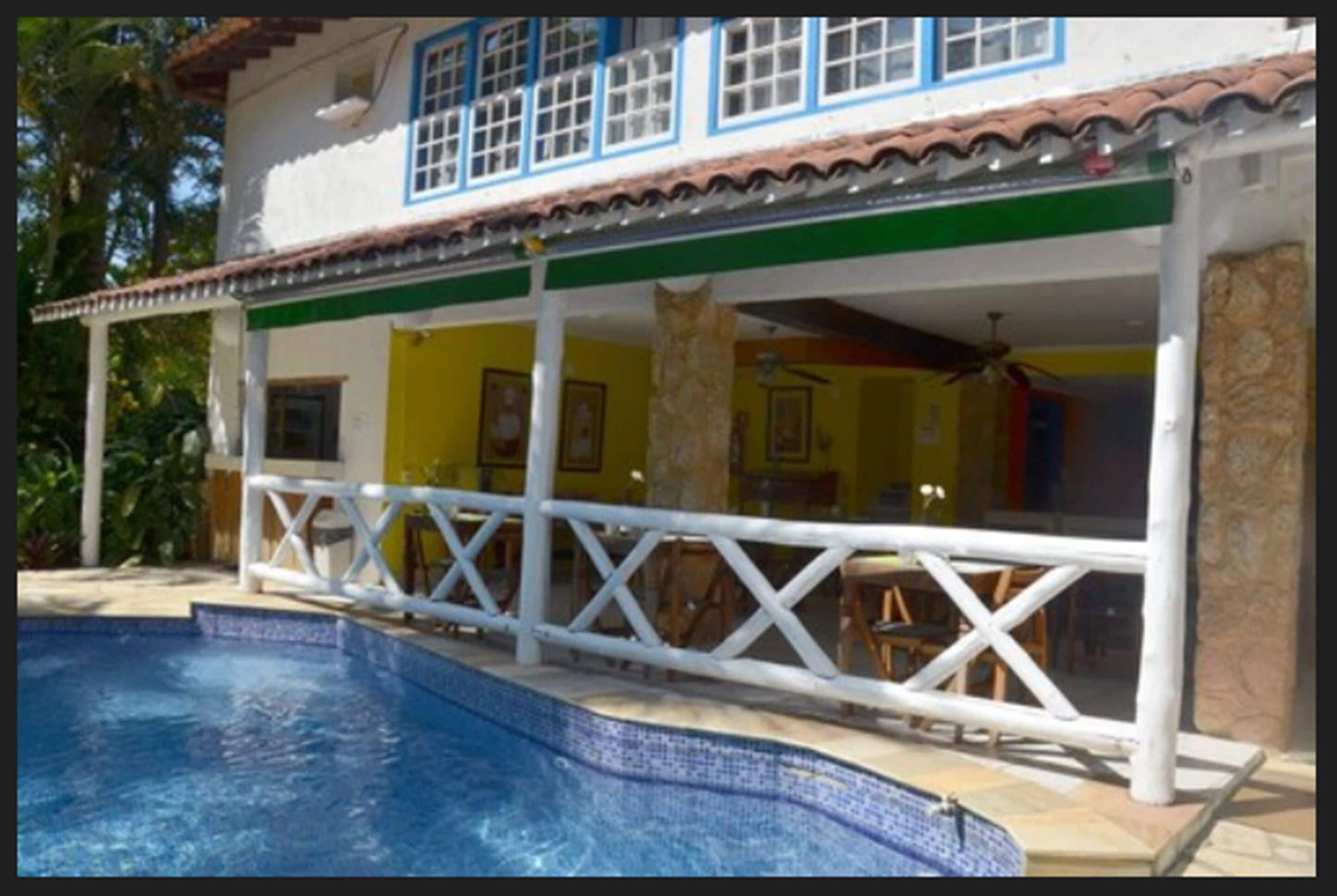 A two-story house with a swimming pool, a covered patio, and a dining area.