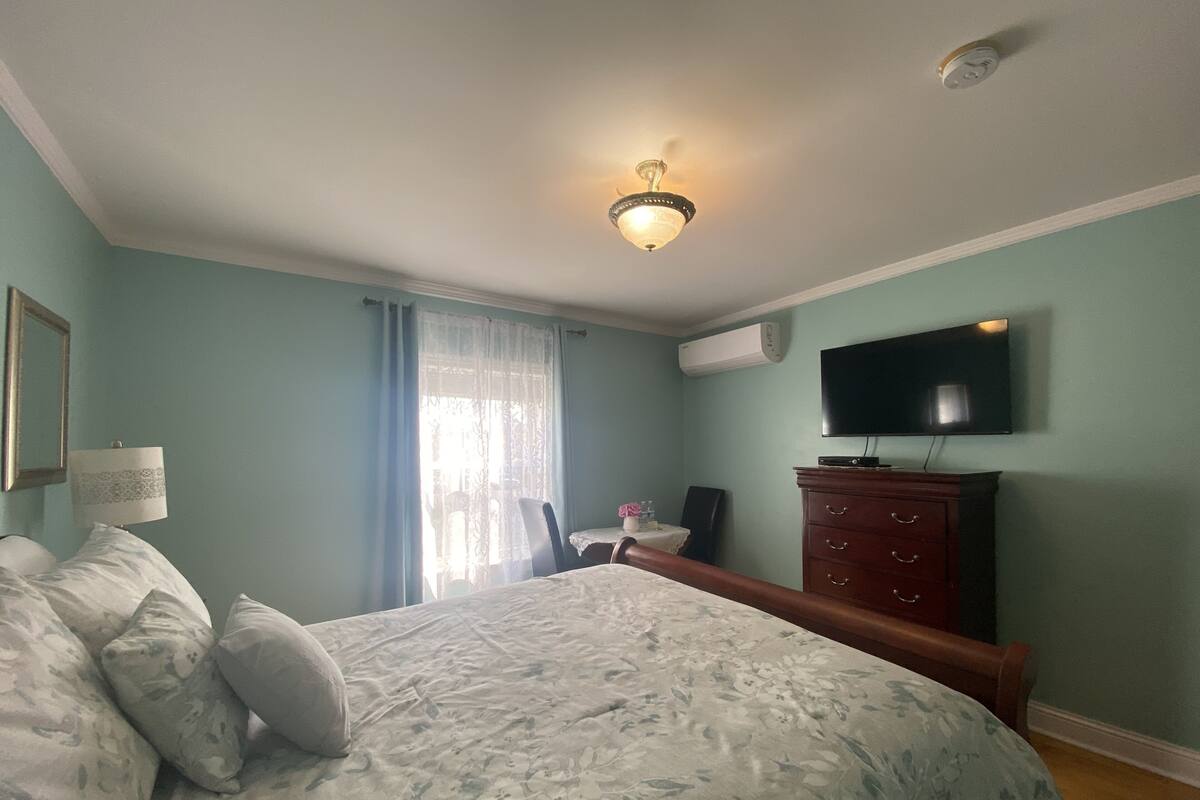 Ein Schlafzimmer mit Bett, Schminktisch, Fernseher und Klimaanlage.