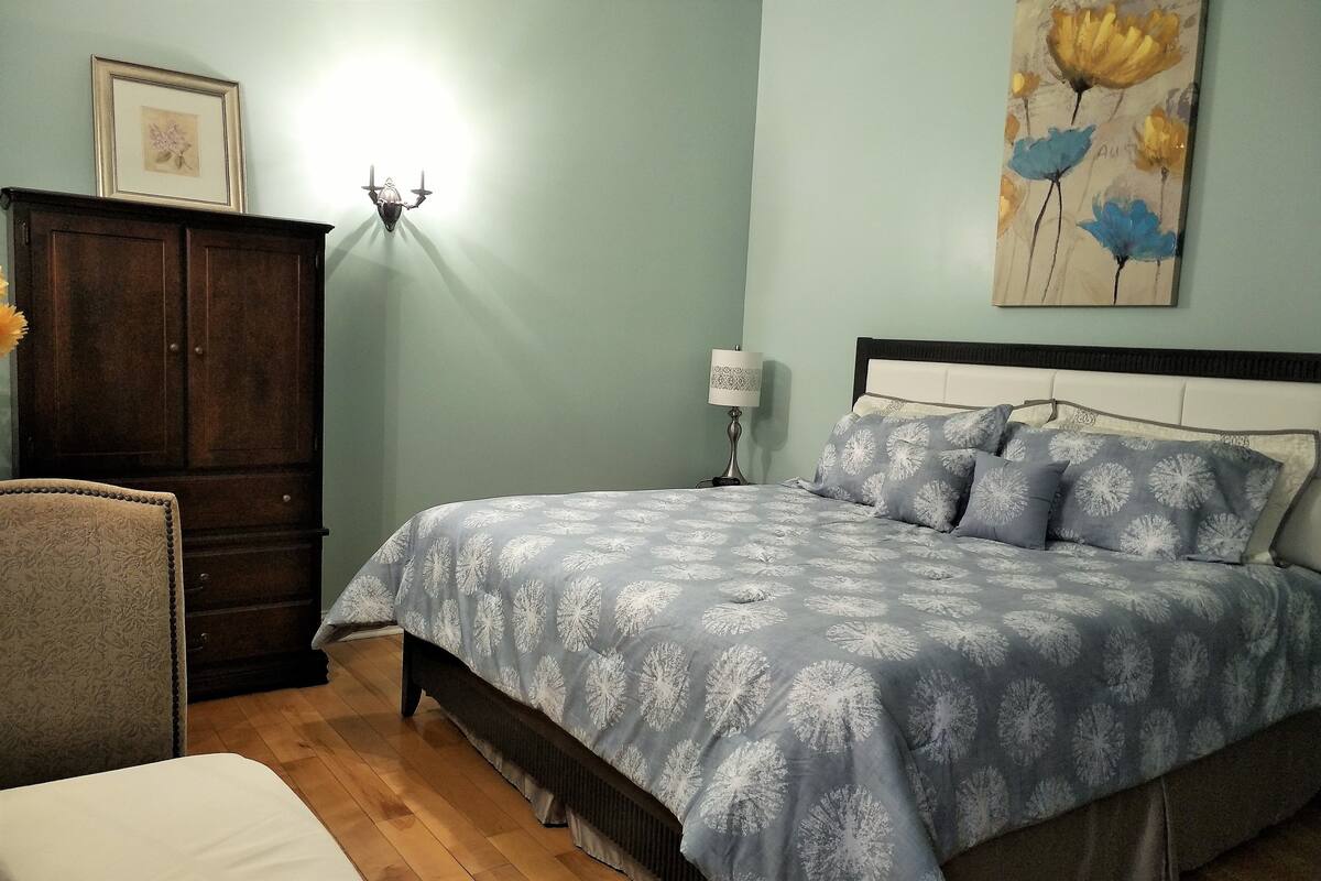 Ein Schlafzimmer mit Bett, Schminktisch, Stuhl und Wandlampe.
