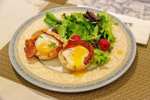 Un plato con dos huevos en un pan, acompañado de una ensalada y una frambuesa.