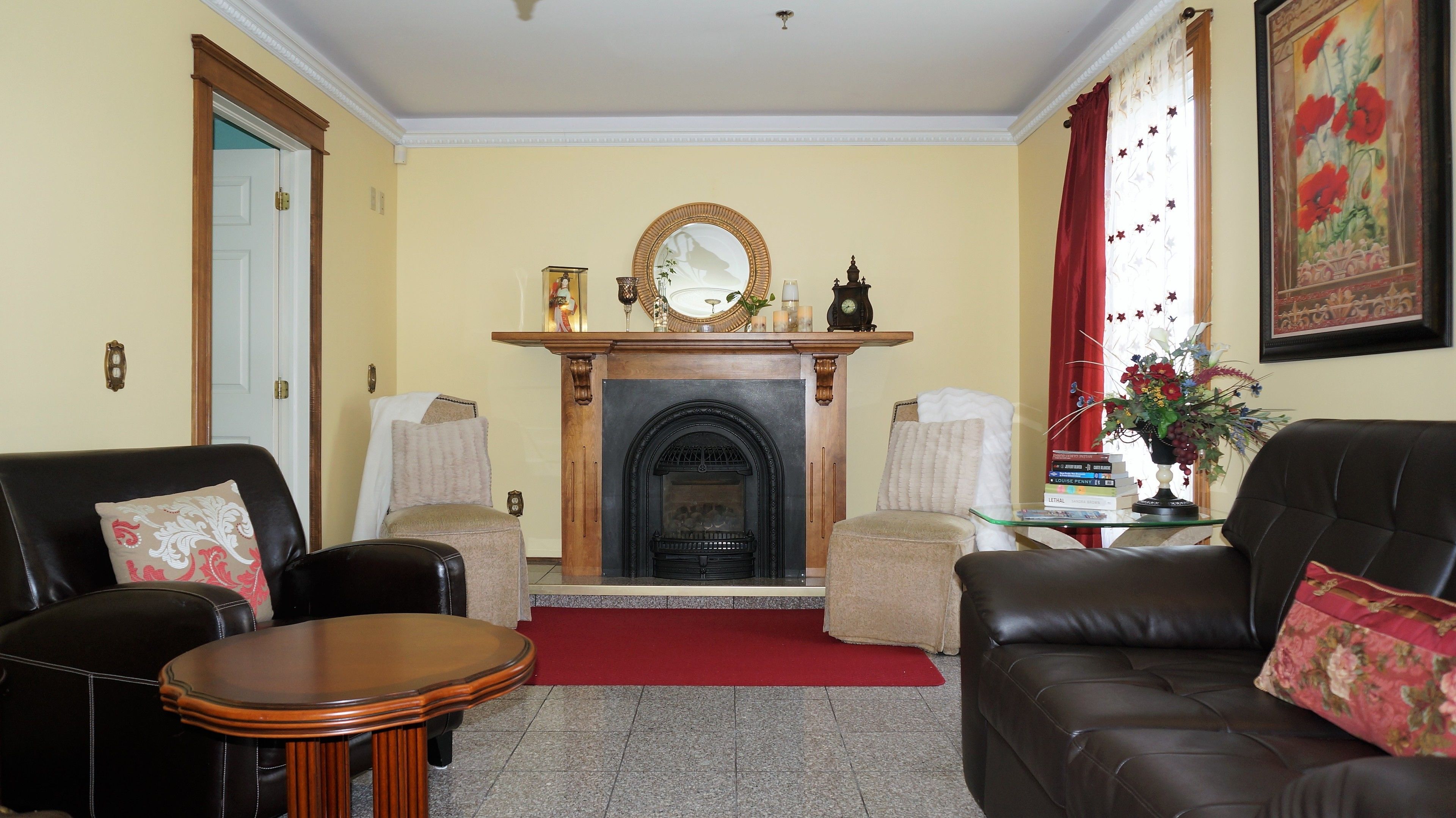 A living room with a fireplace, two leather sofas, a small wooden table, and a red carpet.