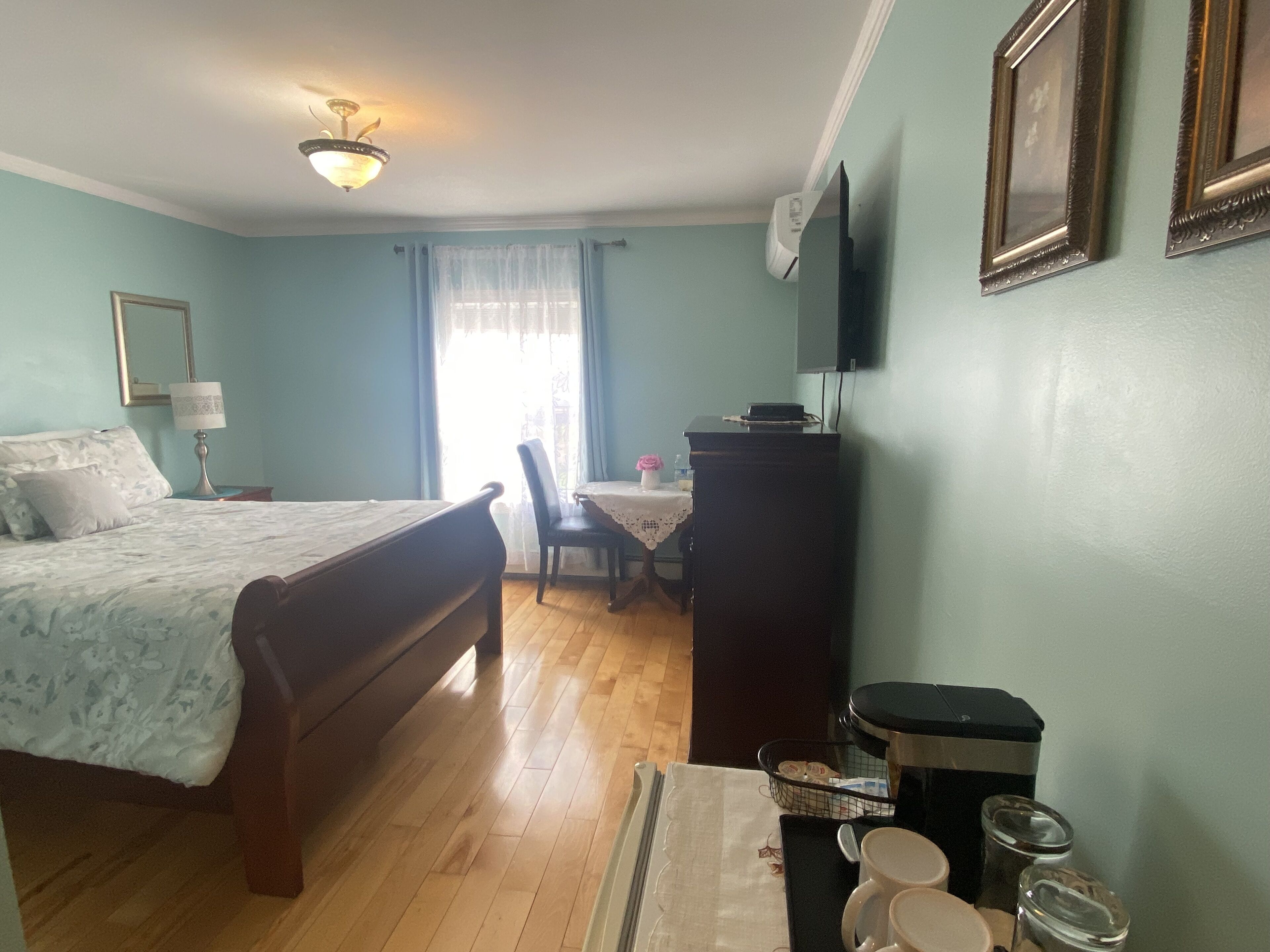 Een hotelkamer met een bed, een bureau, een stoel, een televisie en een kledingkast.