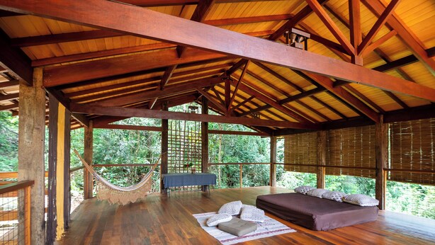 A spacious room with a hammock, a sofa, and a table.