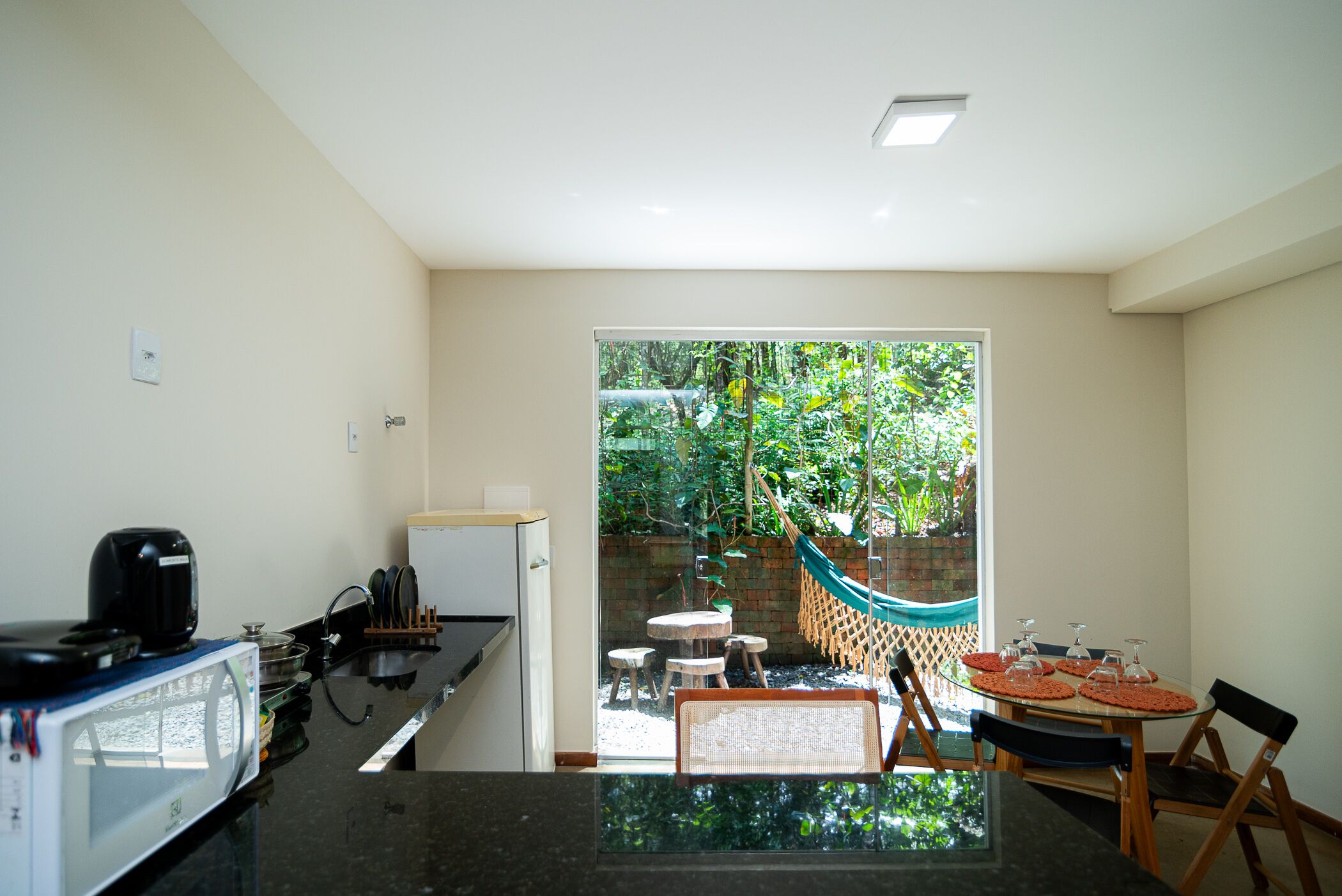 A compact kitchen with a microwave, refrigerator, and a dining area with a table and chairs.