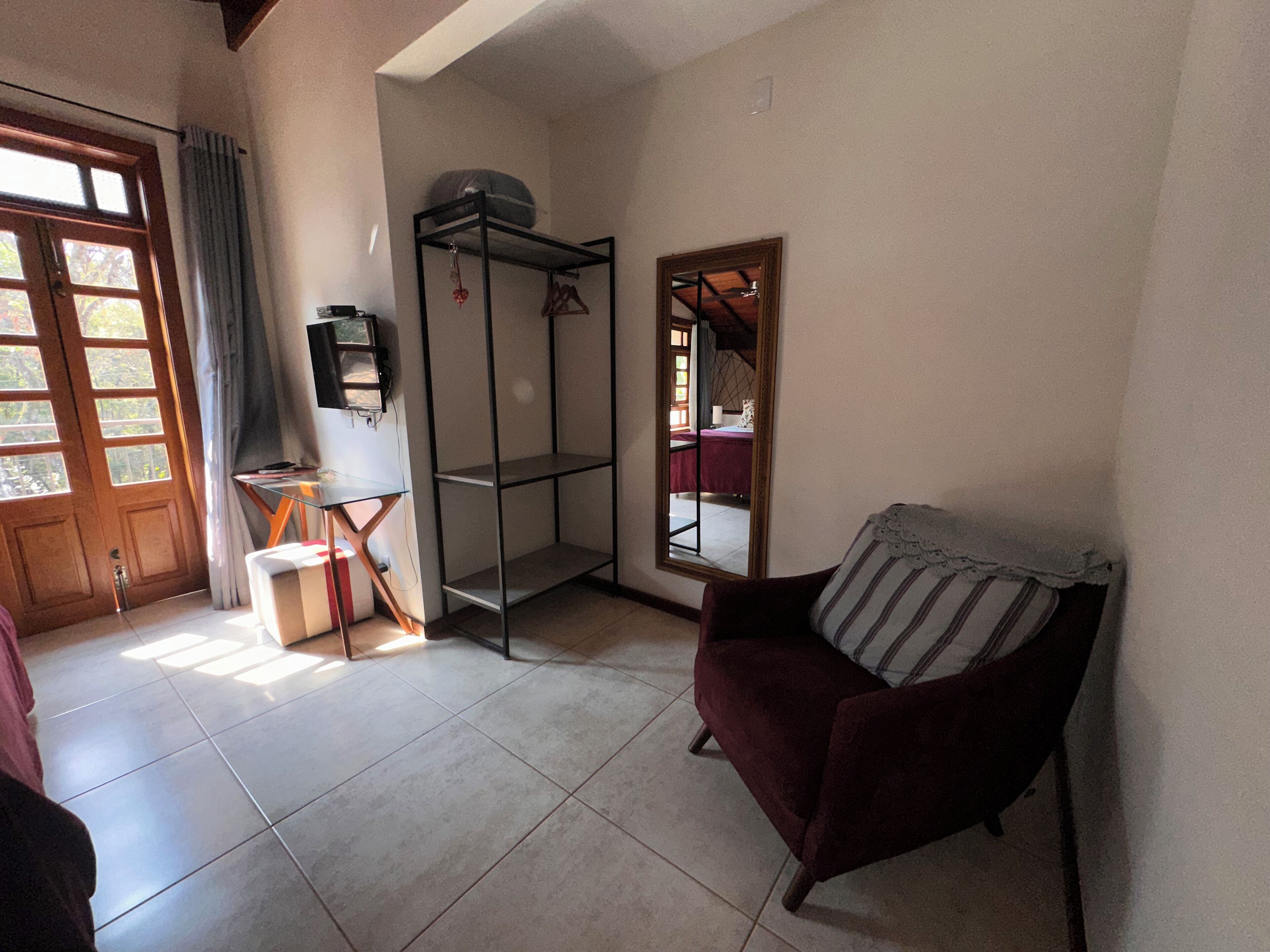 Una sala de estar con un sillón rojo, una mesita, un televisor y un armario.